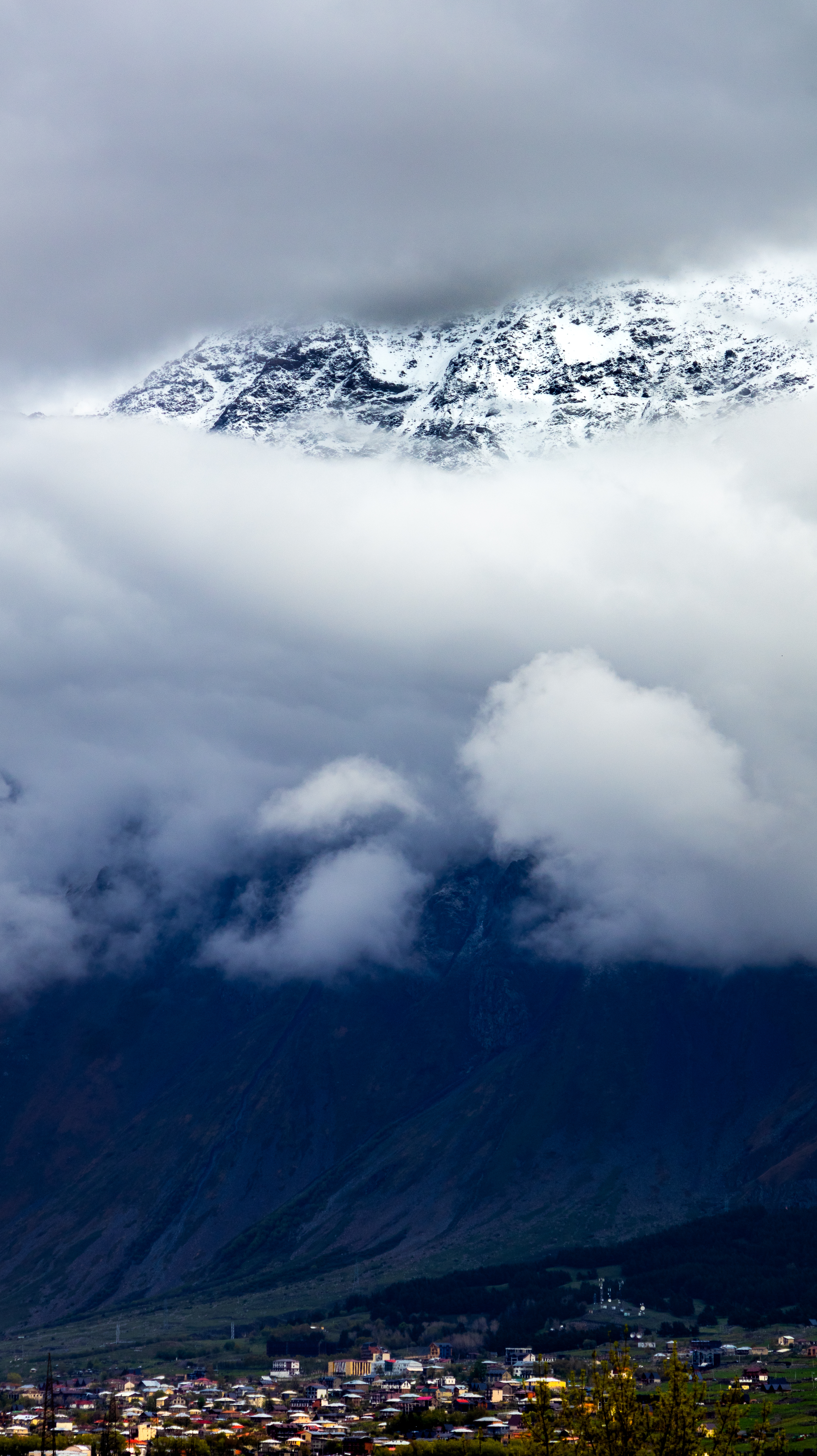 Mountain town beneath dramatic snow-capped peaks, Georgia